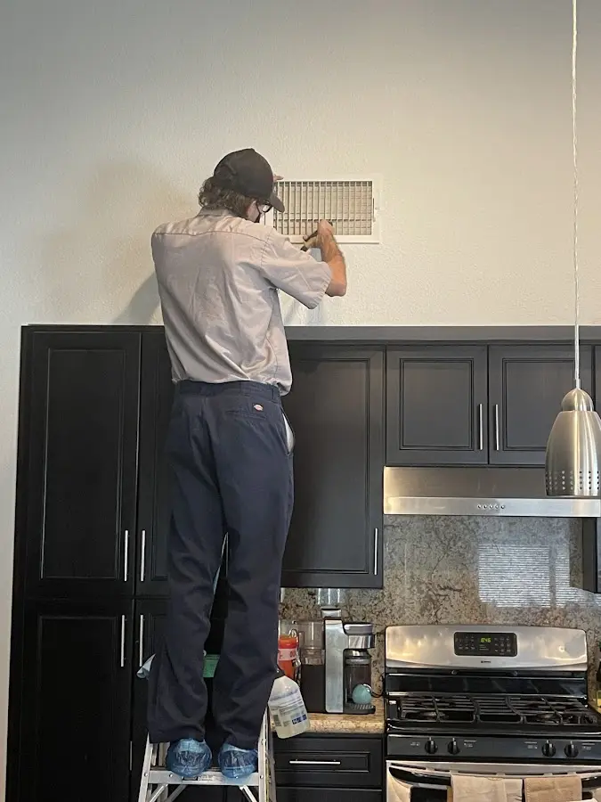 Technician inspecting an air vent during HVAC service in Abbeville